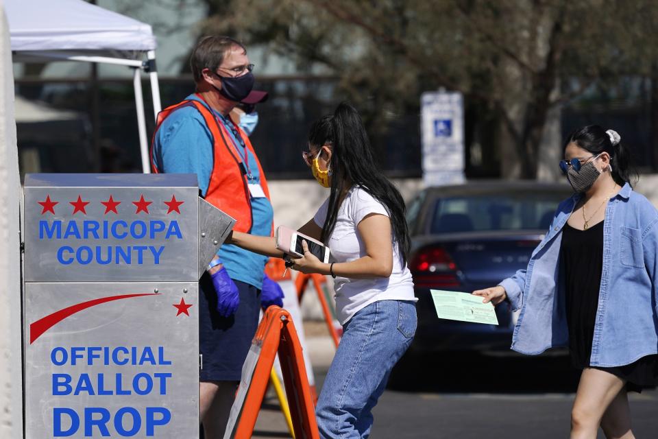 FILE - Voters drop off ballots as volunteers look on at the Maricopa County Recorder's Office on Oct. 20, 2020, in Phoenix. The Arizona Republican Party is asking the state Supreme Court to rule that vote by mail is unconstitutional. The GOP's request would upend the election procedures used by 90% of voters in a battleground state that will be crucial to determining which party controls the U.S. Senate after the 2022 election. (AP Photo/Ross D. Franklin, File)