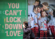 A man walks past a poster in the window of a clothing shop in Manchester, England, Saturday Nov. 28, 2020. A four-week national lockdown to curb the spread of coronavirus is still restricting civil liberties and will put more pressure on shops to attract customers back to shopping streets when restrictions are relaxed in the run-up to Christmas. (Danny Lawson/PA via AP)