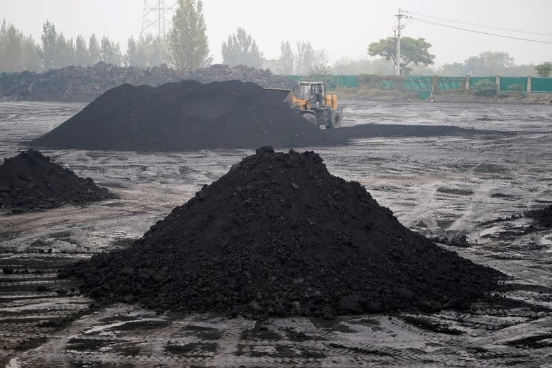 FILE PHOTO: An excavator sift through dunes of low-grade coal near a coal mine in Pingdingshan