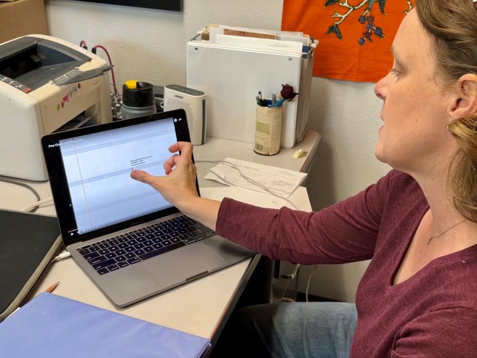 Sara Fraker, associate professor of oboe at the University of Arizona, shows how tree ring data influenced spacing of notes on Pine Chant's scrolling score.