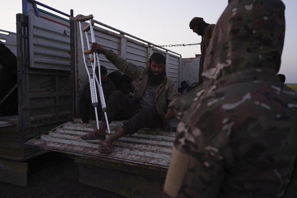 A member of U.S.-backed Syrian Democratic Forces (SDF) watches a wounded man climb off of a truck after being evacuated out of the last territory held by Islamic State militants, outside Baghouz, Syria, Monday, March 4, 2019. Hundreds of people including IS fighters evacuated their last foothold in eastern Syria hours after U.S.-backed Syrian fighters said they were forced to slow their advance because the extremists are using civilians as human shields.(AP Photo/Andrea Rosa)