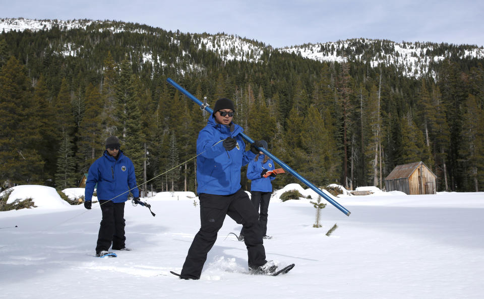 Sean de Guzman, center, chief of snow surveys for the California Department of Water Resources, uses a tape measure to measure the distance between locations to take one of several snowpack samples, during the first snow survey of the season at Phillips Station near Echo Summit, Calif., Thursday, Jan. 2, 2020. The survey found the snowpack at 33.5 inches deep with a water content of 11 inches which is 97% of average at this location at this time of year. Also seen are DWR's Ramesh Gautam, left, and Lauren Miller, right. (AP Photo/Rich Pedroncelli)