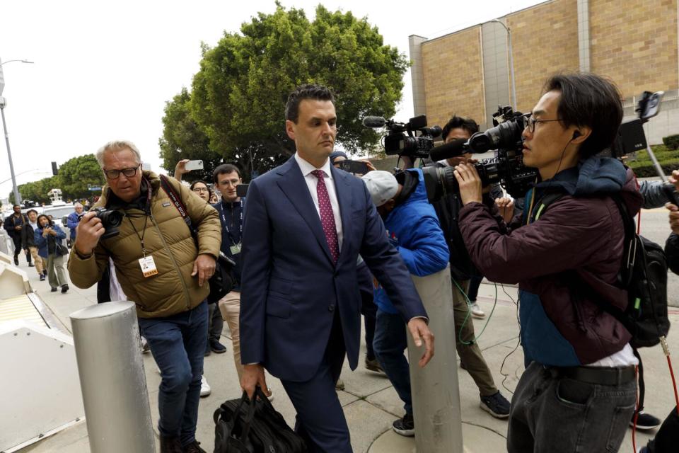 A man in a suit walks outside a courthouse