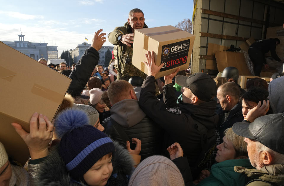 People receive humanitarian aid on central square in Kherson, Ukraine, Tuesday, Nov. 15, 2022. Waves of Russian airstrikes rocked Ukraine on Tuesday, with authorities immediately announcing emergency blackouts after attacks from east to west on energy and other facilities knocked out power and, in the capital, struck residential buildings. (AP Photo/Efrem Lukatsky)