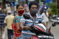 A couple wearing face masks as a precaution against the coronavirus travel on a two wheeler in Kolkata, India, Sunday, Aug. 2, 2020. India is the third hardest-hit country by the COVID-19 pandemic in the world after the United States and Brazil. (AP Photo/Bikas Das)