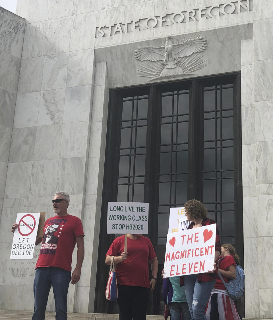 In this photo taken Sunday, June 23, 2019, a small crowd of local Republicans show their support of a Republican walkout outside the Oregon State Capitol in Salem, Ore. The gathering took place only a day after the Senate President ordered the statehouse to close over a "possible militia threat," the latest escalation in a Republican walkout over proposed climate policy that has put Democrats' top legislative priorities at risk. (AP Photo/Sarah Zimmerman)