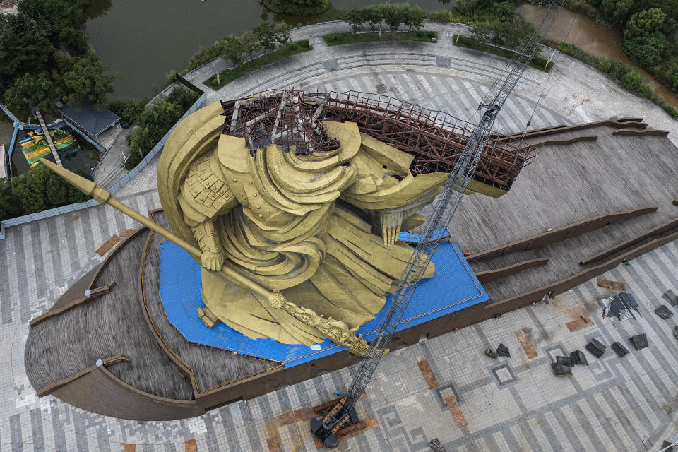 JINGZHOU, CHINA - SEPTEMBER 7：(CHINA OUT) In an aerial view, workers dismantle a 58-meter-high statue of Guan Gong weighing more than 1,200 tons on September 7, 2021 in Jingzhou, Hubei Province, China. The bronze statue of Chinese ancient military general Guan Yu, with the height of 58 meters and weight of 1200 tons, stands at a local park in Jingzhou city. Guan Yu is a famous general in Chinese history, where him was defeated and died during the Three Kingdoms period. The artwork by Han Meilin was completed in 2016. Cracks appeared on it recently and the statue was once criticized as damaging the landscape of the ancient city.  Moving the statue of Guan Gong is expected to cost 155 million RMB. (Photo by Getty Images)