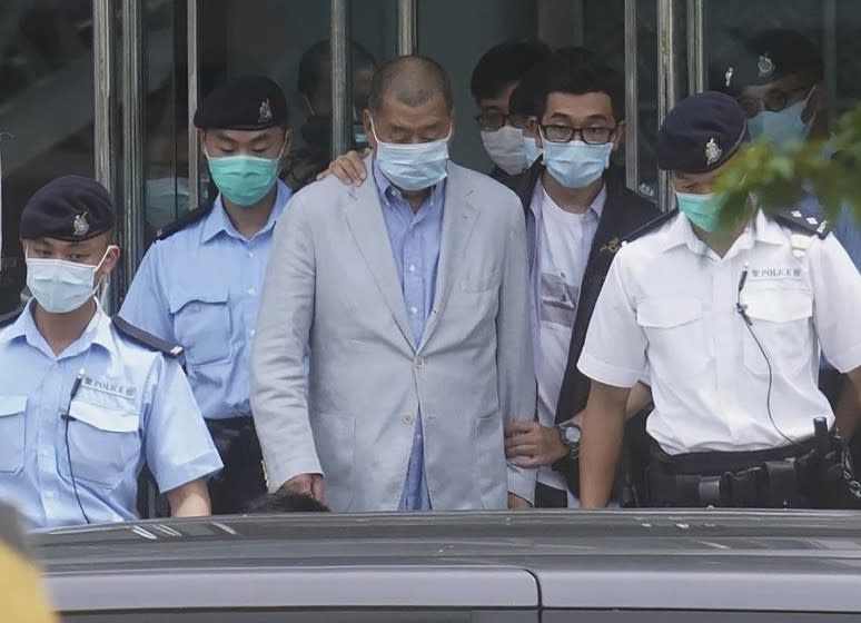 Hong Kong media tycoon Jimmy Lai, center, who founded the local newspaper Apple Daily, is escorted by police from the leave the Apple Daily headquarters in Hong Kong, Monday, Aug. 10, 2020. Lai was arrested Monday on suspicion of collusion with foreign powers, his aide said, in the highest-profile use yet of the new national security law Beijing imposed on the city after protests last year. (AP Photo)