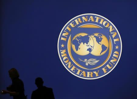 Visitors are silhouetted against the logo of the International Monetary Fund at the main venue for the IMF and World Bank annual meeting in Tokyo October 10, 2012. REUTERS/Kim Kyung-Hoon