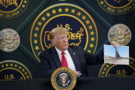 FILE - In this June 23, 2020 file photo, President Donald Trump holds an image of the U.S. border wall being built between the U.S. and Mexico as he participates in a border security briefing at United States Border Patrol Yuma Station in Yuma, Ariz. The Supreme Court is agreeing to review a Trump administration policy that makes asylum-seekers wait in Mexico for U.S. court hearings. As is typical, the court did not comment Monday in announcing it would hear the case. Because the court’s calendar is already full through the end of the year, the justices will not hear the case until 2021. (AP Photo/Evan Vucci)