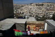 FILE PHOTO: A woman hangs laundry outside her house in the East Jerusalem neighbourhood of Jabal Mukaber November 23, 2010. Jerusalem's Old City (top L) and the East Jerusalem neighbourhoods of Ras al-Amud (R) and Silwan (L) are seen in the background. REUTERS/Ronen Zvulun/File Photo