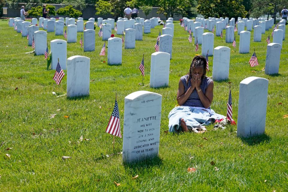 Jennifer Davis of Stafford, Va., wipes her face from the heat as she spends time at the grave of her ex-husband, Staff Sgt. Allen Davis, during a visit to Arlington National Cemetery in Arlington, Va., on Memorial Day, Monday, May 30, 2022.