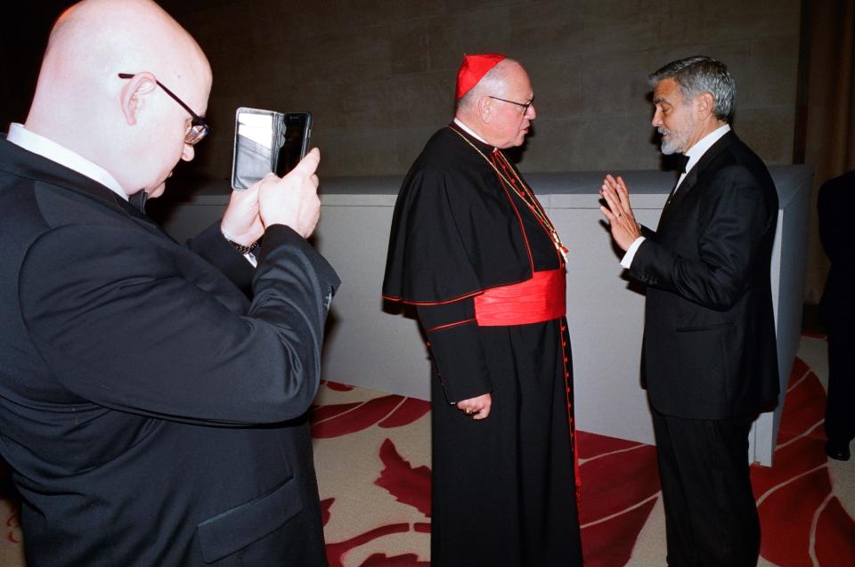 2018 - A Catholicism fan catches George Clooney jawing with Cardinal Dolan on his way into the museum.