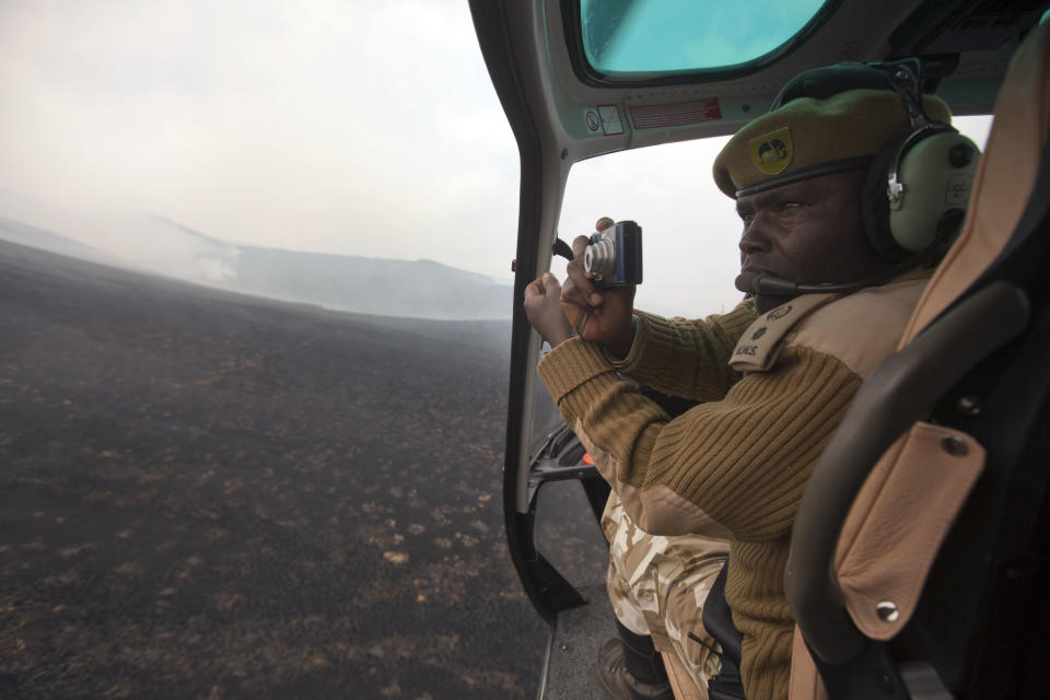 Simon Gitau, deputy warden of Mt. Kenya National Park, takes photographs of forest fires from a helicopter, in order to show to those on the ground trying to locate and extinguish the fires, over the slopes of Mount Kenya, the second-highest peak in Africa at 5,199 meters (17,057 feet), in Kenya Tuesday, March 20, 2012. Fires that have been raging across Mount Kenya may have been set by poachers trying to create a diversion from their illegal attacks on animals, a wildlife official said Tuesday. (AP Photo/Ben Curtis)