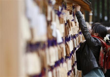 A girl hooks an "Ema" or a small wooden plaque, on which her wishes are written, at the Yasukuni Shrine in Tokyo January 1, 2014. REUTERS/Yuya Shino