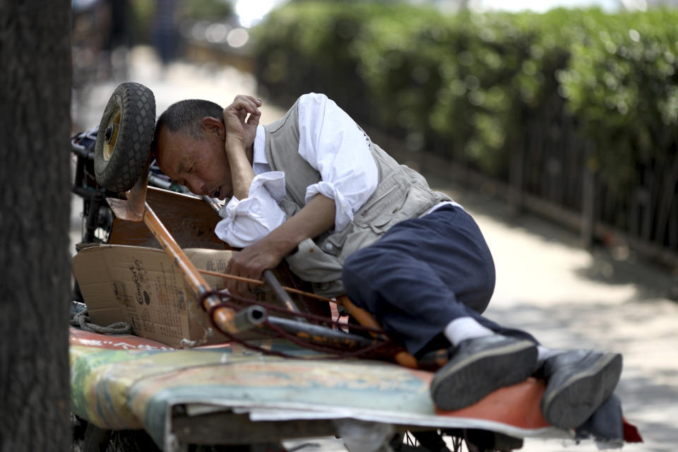 A delivery man naps with his trolley in Beijing on Thursday, May 16, 2019. China's factory output and consumer spending weakened in April as a tariff war with Washington intensified, adding to pressure on Beijing to shore up shaky economic growth. (AP Photo/Ng Han Guan)