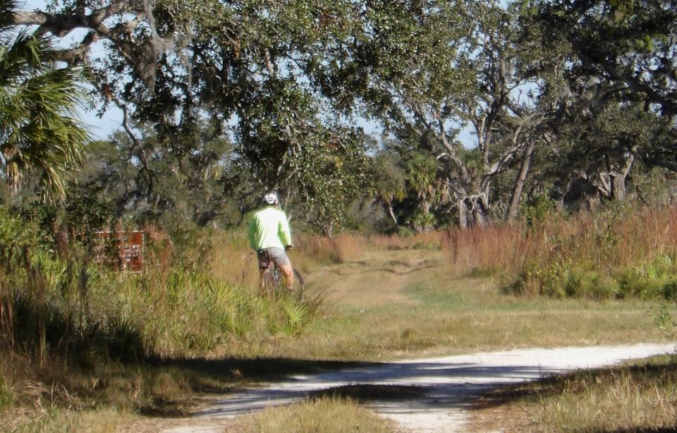 A cyclist pauses at the intersection of Ranch House Road and All Weather Road at Myakka River State Park. The intersection will be receiving a trail marker.