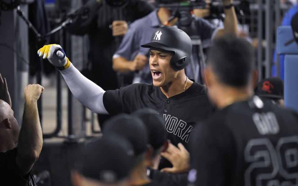 New York Yankees' Aaron Judge is congratulated by teammates in the dugout after hitting a solo home run during the third inning of the team's baseball game against the Los Angeles Dodgers on Friday, Aug. 23, 2019, in Los Angeles. (AP Photo/Mark J. Terrill)