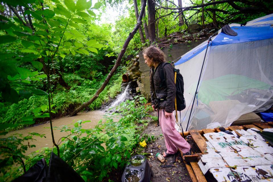 Ashley Heath, a person facing homelessness in Brattleboro, Vt., looks over an area where she and others would camp under the Elm Street Bridge near the Whetstone Brook that flooded, Monday, July 10, 2023. In her three months of camping in that spot, this is the worst she has seen the water level. (Kristopher Radder/The Brattleboro Reformer via AP)