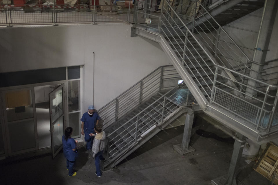 Night shift nurses take a smoke break outside the entrance to the COVID-19 ICU at the La Timone hospital during the early hours of the morning in Marseille, southern France, Friday, Nov. 13, 2020. (AP Photo/Daniel Cole)