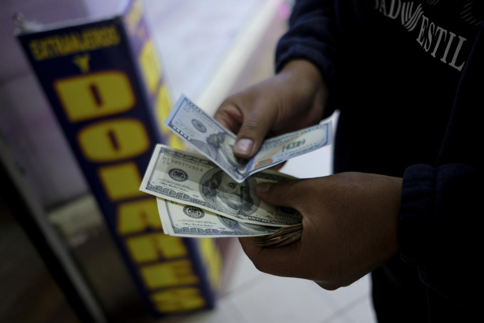 A man holds dollars at a currency exchange shop in La Paz, Bolivia, Friday, June 28, 2024, days after Army troops stormed the government palace in what President Luis Arce called a coup attempt. (AP Photo/Carlos Sanchez)