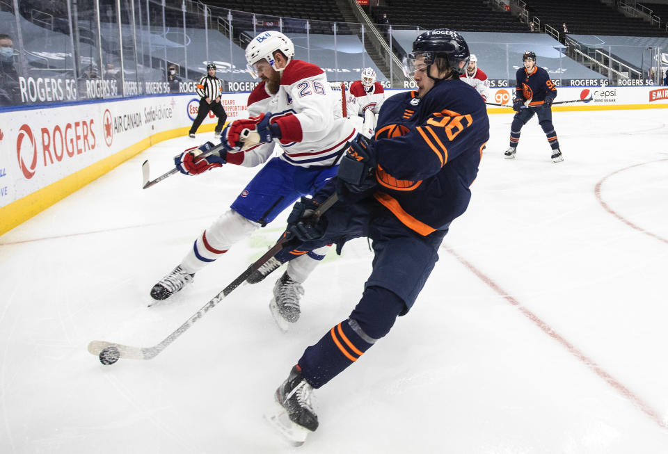 Edmonton Oilers' Kailer Yamamoto (56) and Montreal Canadiens' Jeff Petry (26) compete for the puck during the second period of an NHL hockey game Wednesday, April 21, 2021, in Edmonton, Alberta. (Jason Franson/The Canadian Press via AP)