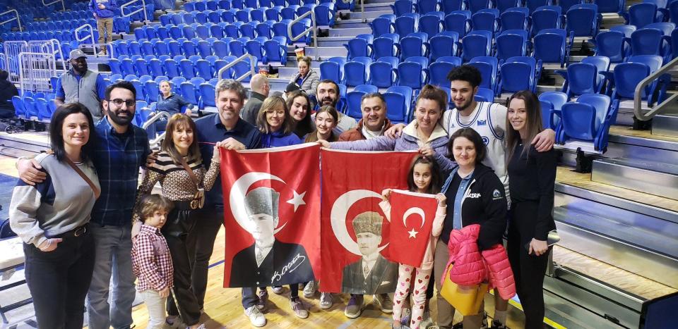 Okay Djamgouz poses for a photo with members of the Des Moines' Turkish community after the Drake basketball game against Belmont.