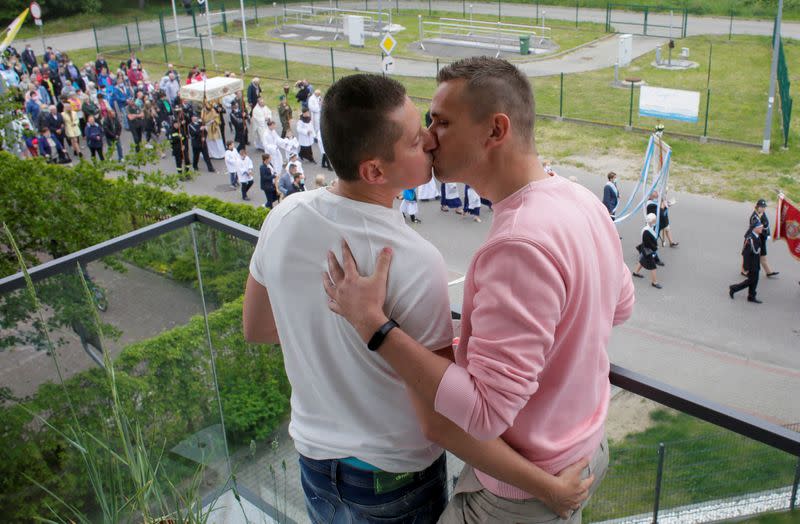 Gay married couple Dawid Mycek and Jakub Kwiecinski kiss on the balcony of their apartment