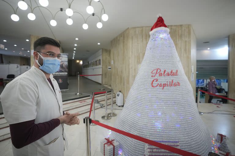 Un miembro del personal médico se encuentra junto a un árbol de Navidad hecho con envases vacíos de vacuna COVID-19 en un centro de vacunación en la capital de Rumania