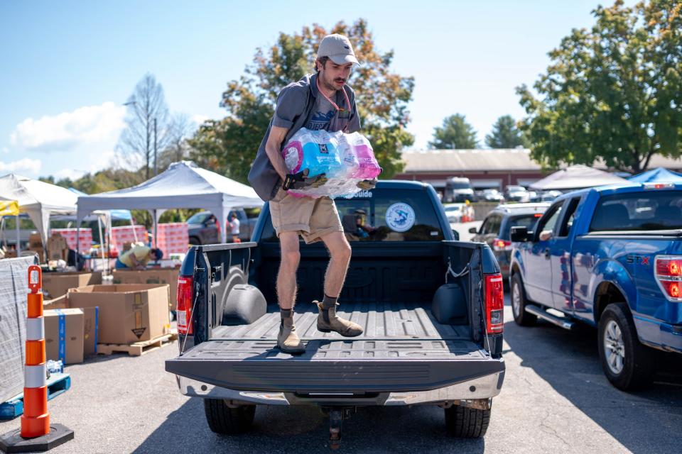 Oct 5, 2024; Asheville, NC, USA; Barek Reep, with MANNA, carries waters off a truck as MANNA FoodBank provide resources to residents at the WNC Farmers Market during the aftermath of flooding caused by the remnants of Hurricane Helene. Mandatory Credit: Nathan Fish-USA TODAY