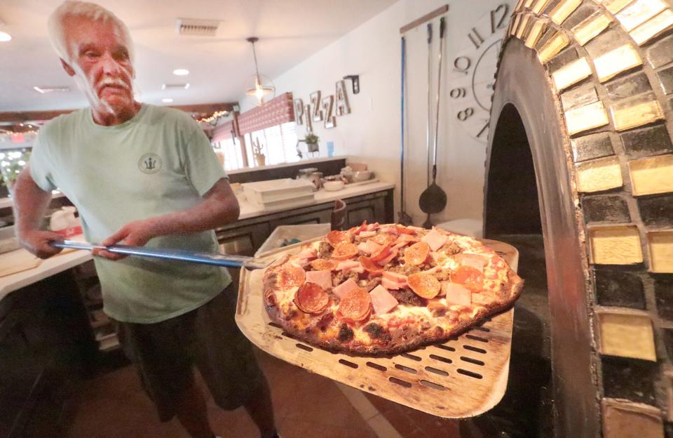 Scott Chase pulls a pizza out of the brick oven at Paradise Pizza. “We’re making everything ourselves,” Scott Chase said.  "If it costs me 50 cents more to use a quality product, so be it.”