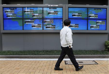A pedestrian walks past electronic boards showing various countries' share prices outside a brokerage in Tokyo February 6, 2014. REUTERS/Toru Hanai