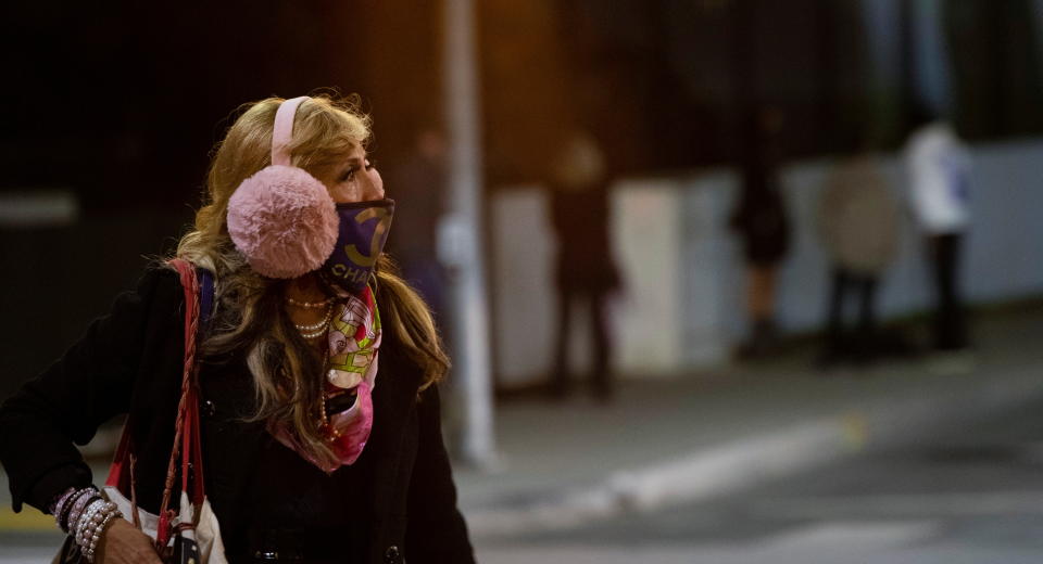 A woman wearing a protective face mask and earmuffs crosses the street during the outbreak of the coronavirus disease (COVID-19), in Beverly Hills, California, U.S., November 20, 2020. REUTERS/Mario Anzuoni