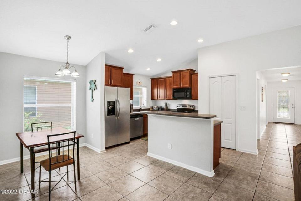 Tile runs throughout the main living areas and the large living/dining area that connects directly to the kitchen, featuring stainless-steel appliances and a breakfast bar.