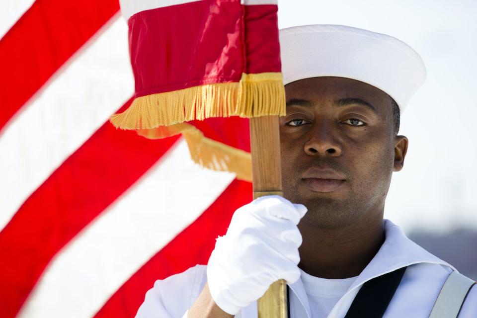 Seaman Daniel Odoi of the Navy Operational Support Center of New York City presents the American flag on Memorial Day 2013. AP Photo/John Minchillo