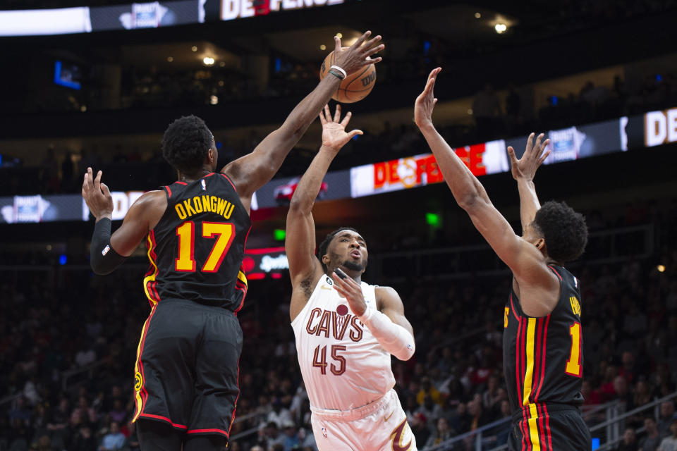 Cleveland Cavaliers guard Donovan Mitchell (45) shoots over Atlanta Hawks forward Onyeka Okongwu (17) and forward De'Andre Hunter during the second half of an NBA basketball game, Tuesday, March 28, 2023, in Atlanta. (AP Photo/Hakim Wright Sr.)