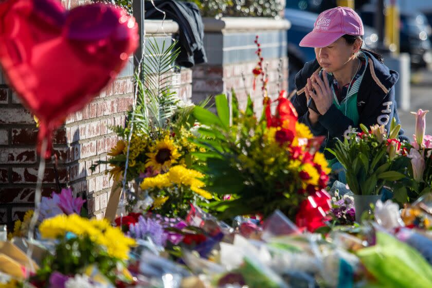 A woman pays her respect at a make-shift memorial for victims of mass shooting in Monterey Park, CA.