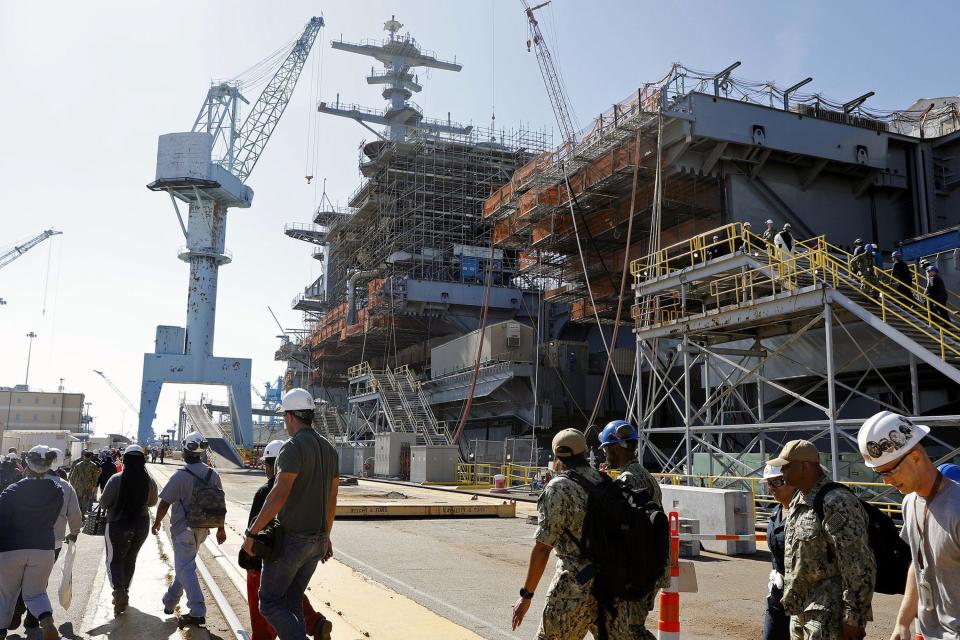 Newport News Shipbuilding workers and Navy sailors walk past USS George Washington.