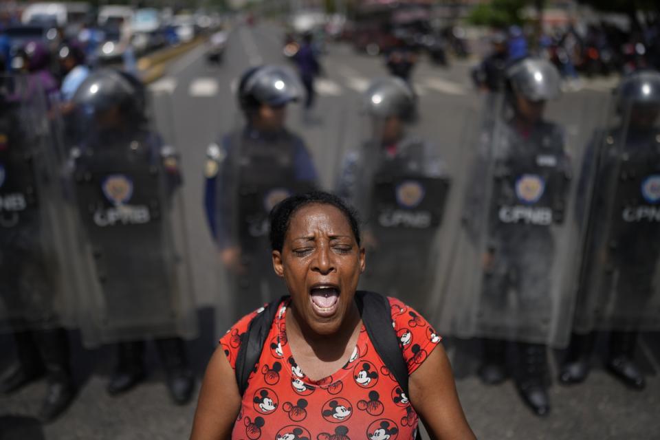 The family member of a prisoner on hunger strike chants during a demonstration against conditions in the jails and slow judicial procedures, as police form a cordon to keep the protesters from blocking Bolivar Avenue in Caracas, Venezuela, June 12, 2024. (AP Photo/Ariana Cubillos)