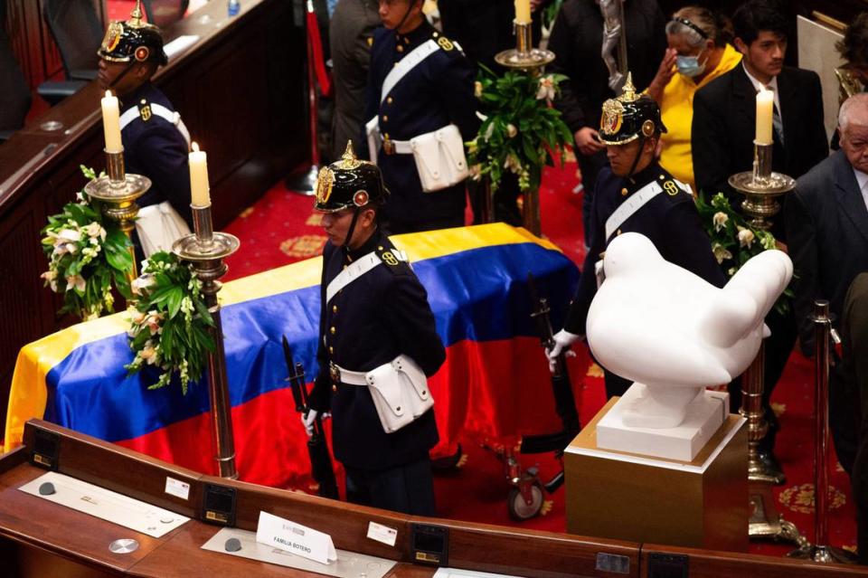 Varias personas pasan detrás del ataúd de Fernando Botero mientras el difunto artista colombiano yace dentro del Congreso Nacional, donde se ve su escultura “La Paloma de la Paz” junto al ataúd durante su velorio en Bogotá, Colombia, el 22 de septiembre de 2023.