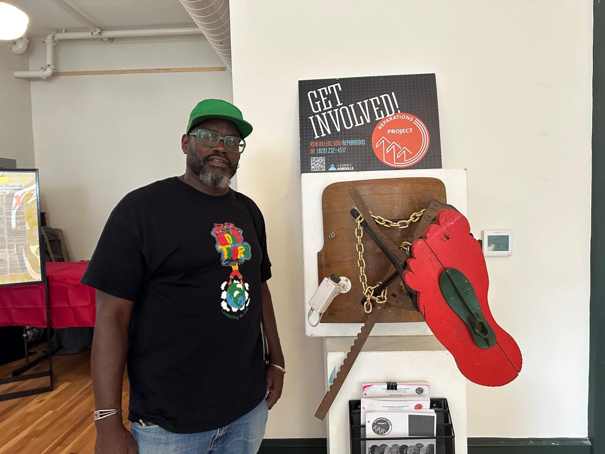 Dewayne Barton poses next to his sculpture built to represent the reparations process in YMI's art gallery June 19.