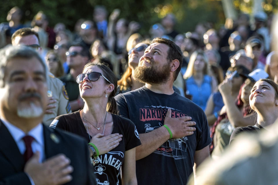 People cover their hearts during the national anthem during the dedication of the Borderline Healing Garden at Conejo Creek Park in Thousand Oaks, Calif., Thursday, Nov. 7, 2019. The dedication marked the anniversary of a fatal mass shooting at a country-western bar a year earlier. (Hans Gutknecht/The Orange County Register via AP)