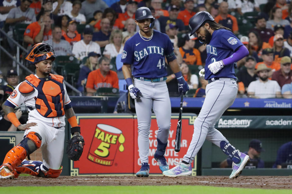 Seattle Mariners' J.P. Crawford, right, touches home plate after hitting a home run as Houston Astros catcher Martin Maldonado, left, and Mariners' Julio Rodriguez (44) look on during the third inning of a baseball game Thursday, July 6, 2023, in Houston. (AP Photo/Michael Wyke)