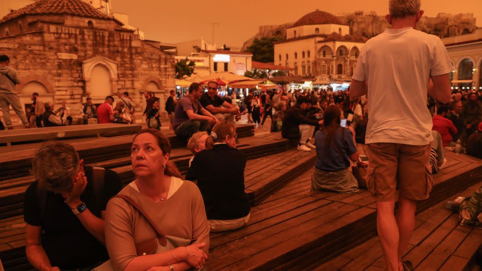 People gather outdoors as dust covers Athens, on April 23, 2024. - George Vitsaras/EPA-EFE/Shutterstock