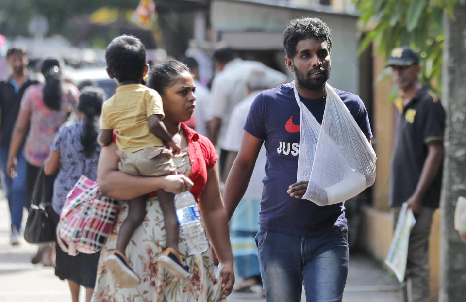 Sri Lankans walk past the National Hospital during a day long token strike by the members of Government Medical Officers Association in Colombo, Sri Lanka, Wednesday, Sept. 18, 2019. The trade union action is to demand the government resolve salary anomalies faced by the doctors serving at state-run hospitals. (AP Photo/Eranga Jayawardena)