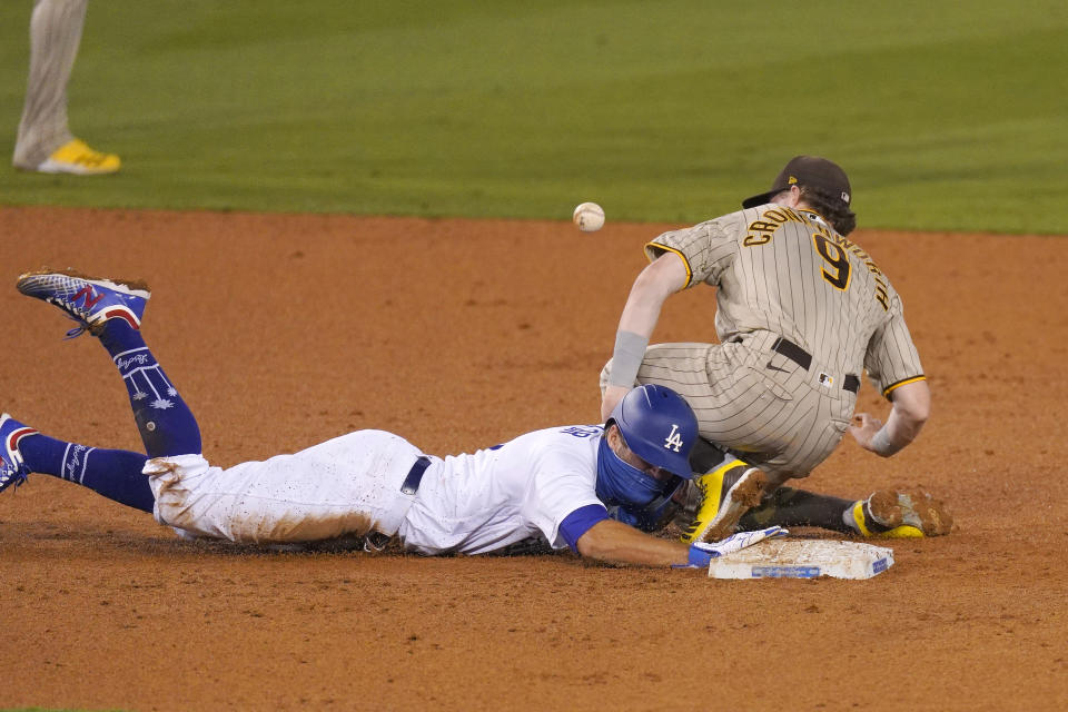 San Diego Padres shortstop Jake Cronenworth, right, loses the ball and is unable to tag out Los Angeles Dodgers' Chris Taylor as he dives back to second during the seventh inning of a baseball game Monday, Aug. 10, 2020, in Los Angeles. Padres catcher Austin Hedges was charged with an error the throw and Taylor advanced to third on the play. (AP Photo/Mark J. Terrill)