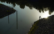 A man walks along a canal near the Hidalgo County Irrigation District #3 pump station that feeds water from the Rio Grande, Tuesday, Sept. 14, 2021, in Hidalgo, Texas. Under a 1944 treaty, Mexico and the U.S. share water from the Rio Grande for use in agriculture, industries and households. Since then, the border cities of McAllen, Brownsville, Reynosa and Matamoros have ballooned — along with their water needs. (AP Photo/Eric Gay)