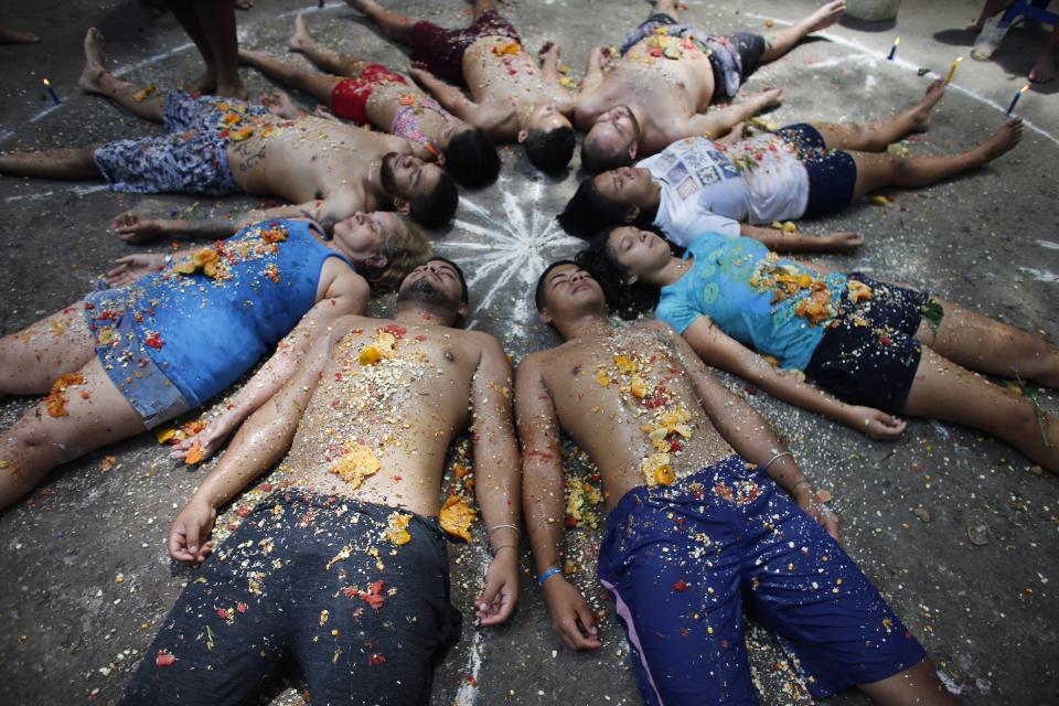 In this photo taken Oct. 13, 2019, followers of Maria Lionza lie amid candles and white powder designs inside a circle called an oracle during a ritual for prosperity on Sorte Mountain where followers of indigenous goddess Maria Lionza gather annually in Venezuela's Yaracuy state. Venezuela is predominantly Roman Catholic, and the church disapproves of the folk religion but has long since abandoned its attempts to suppress it. (AP Photo/Ariana Cubillos)