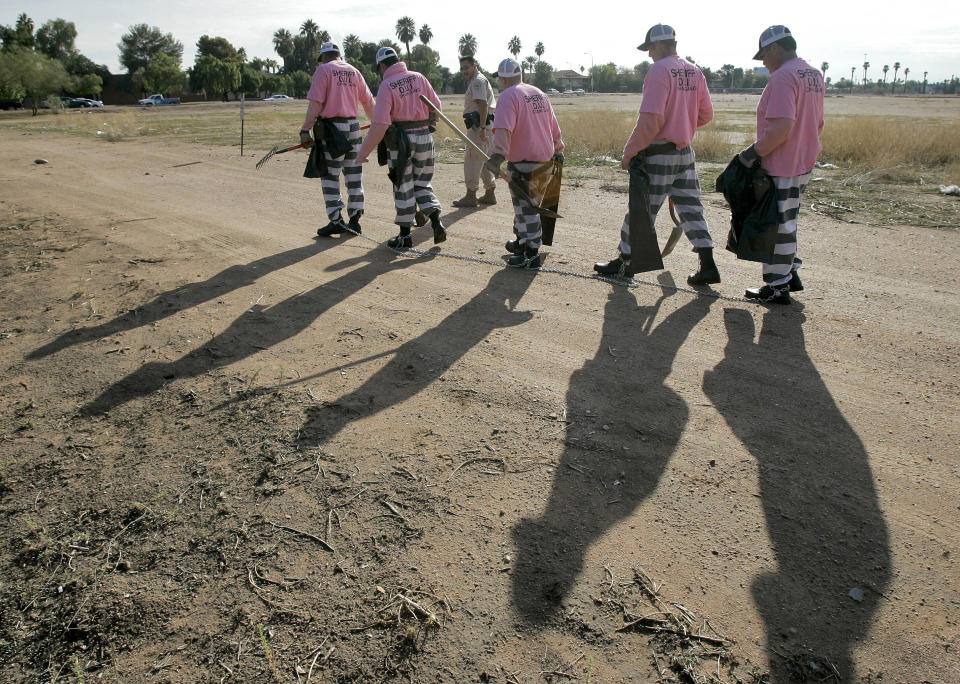 FILE- In this Dec. 11, 2007, file photo, members of the Maricopa County DUI chain gang are escorted to their assignment in Phoenix. As the nation on Thursday, June 17, 2021 officially made Juneteenth a federal holiday, honoring when the last enslaved Black people learned they were free, lawmakers are reviving calls to end a loophole in the Constitution that has allowed another form of slavery to thrive. (AP Photo/Matt York, File)