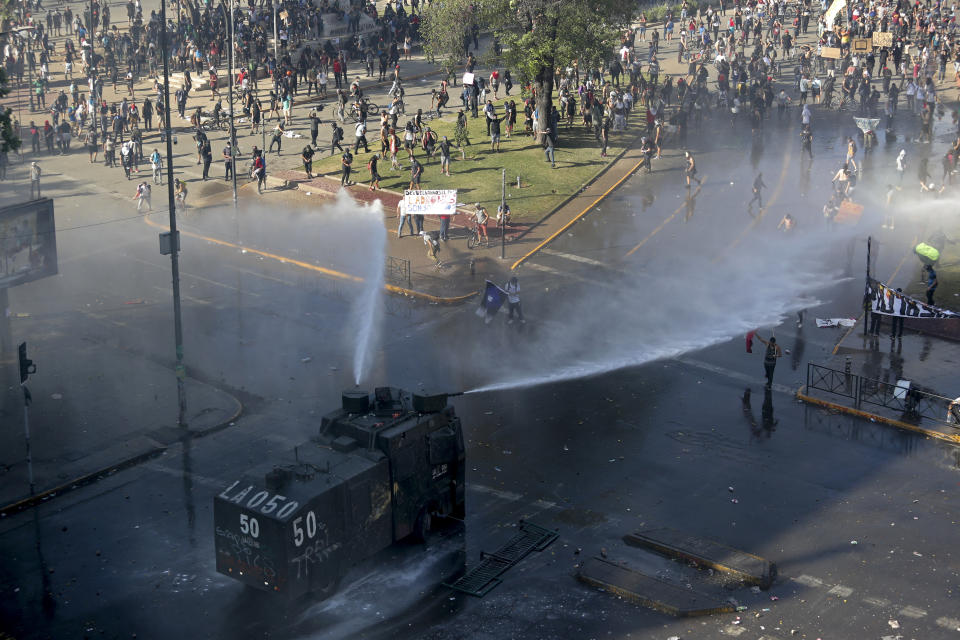 A police truck sprays water canons at protesters, amid ongoing demonstrations triggered by an increase in subway fares in Santiago, Chile, Monday, Oct. 21, 2019. Protesters defied an emergency decree and confronted police in Chile’s capital on Monday, continuing disturbances that have left at least 11 dead and led the president to say the country is “at war.” (AP Photo/Miguel Arenas)